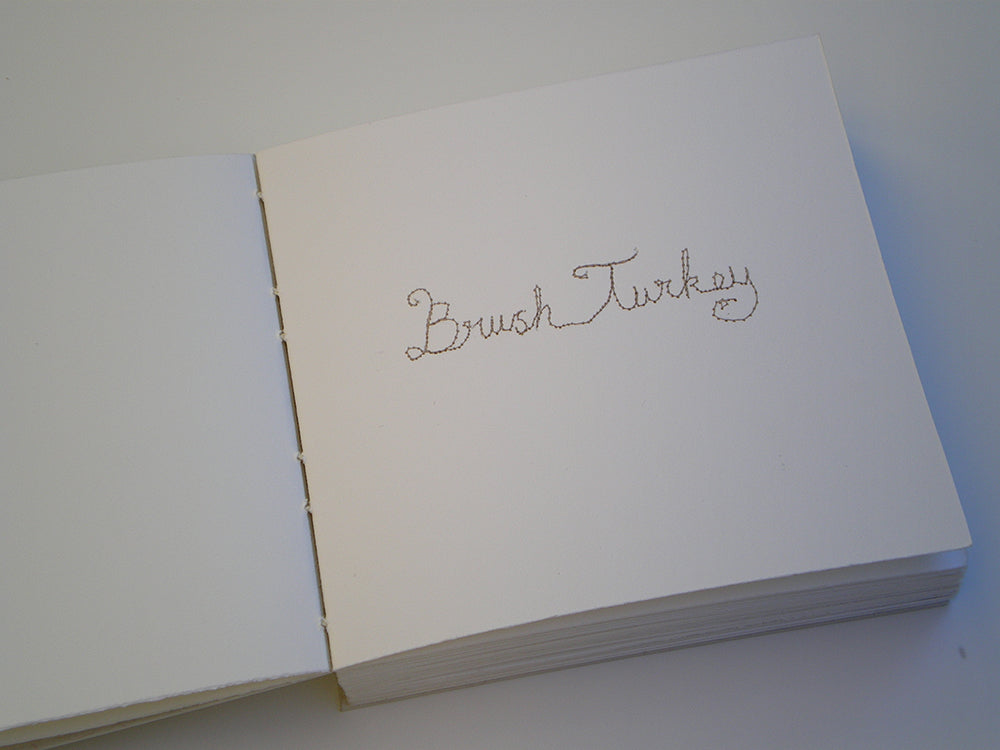 White book with 'Brush Turkey' embroidered on a white background