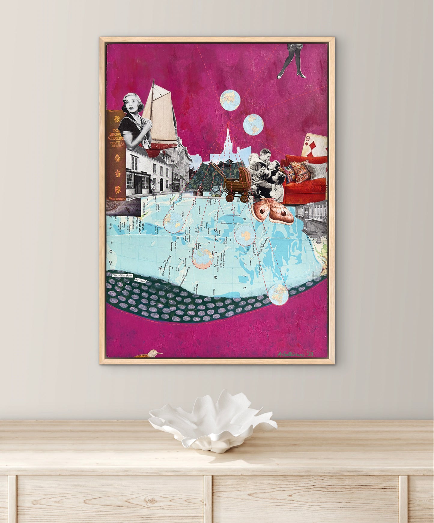 Collage art piece on a wall above a wooden cabinet with a decorative bowl.