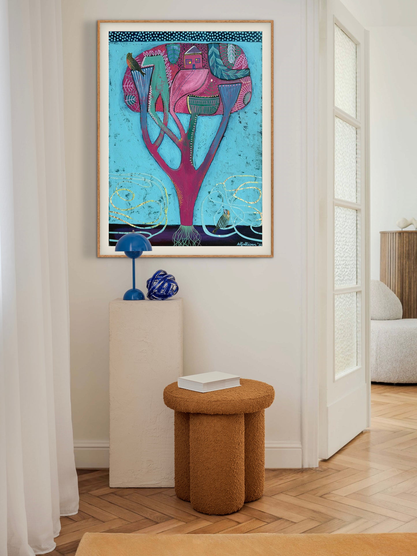 Colorful abstract art piece on a wall in a room with a stool and decor items.