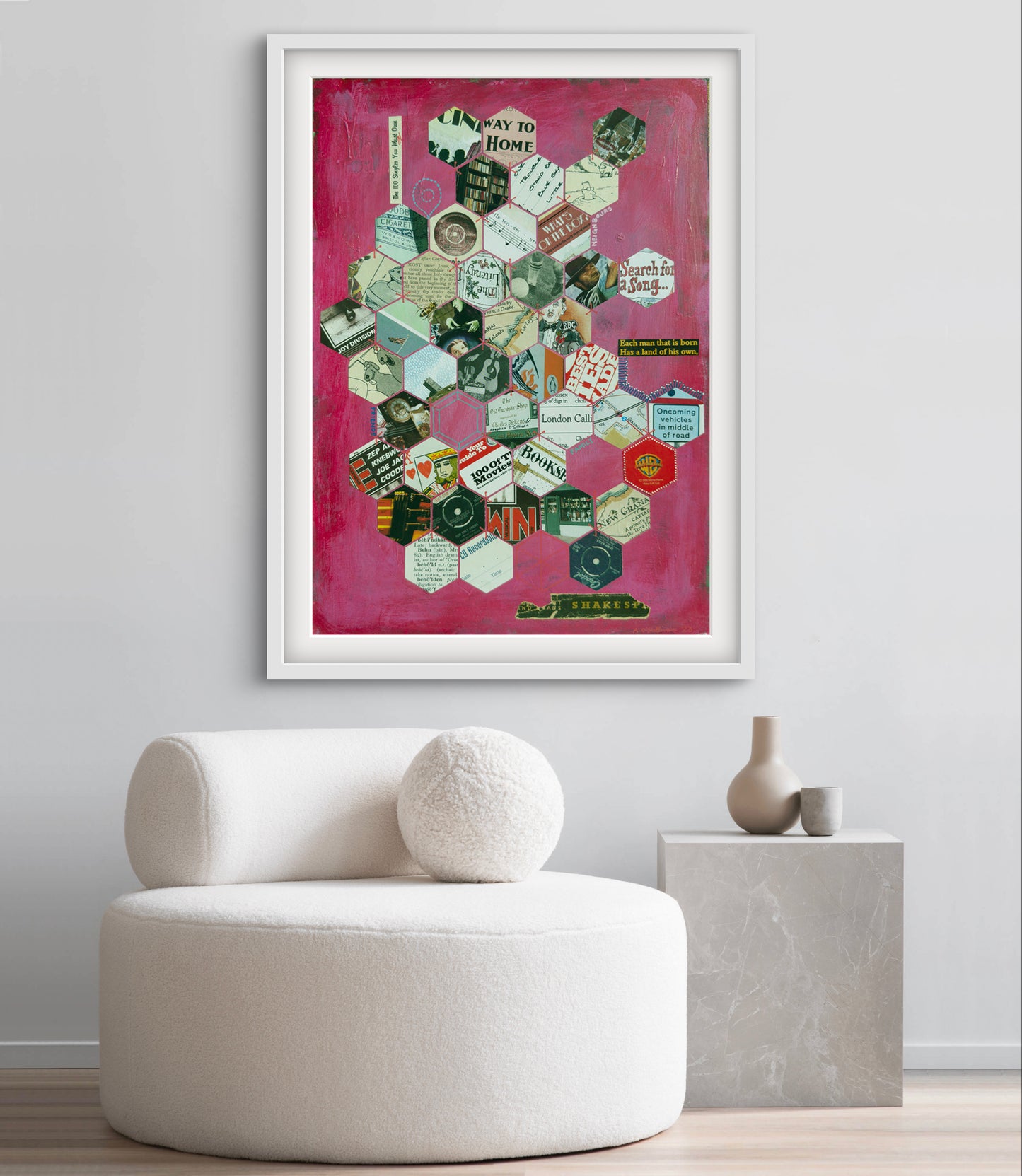 Framed collage art on a wall above a white chair